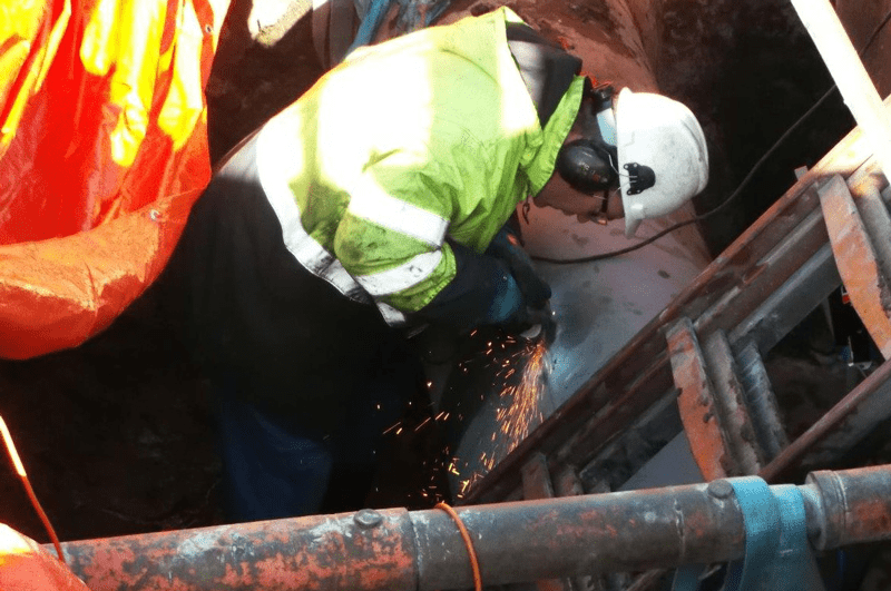 Technicians remove the crack in the seam weld with a grinder to prepare the surface of a carbon steel crude oil pipeline for a composite repair. Photos courtesy of CSNRI